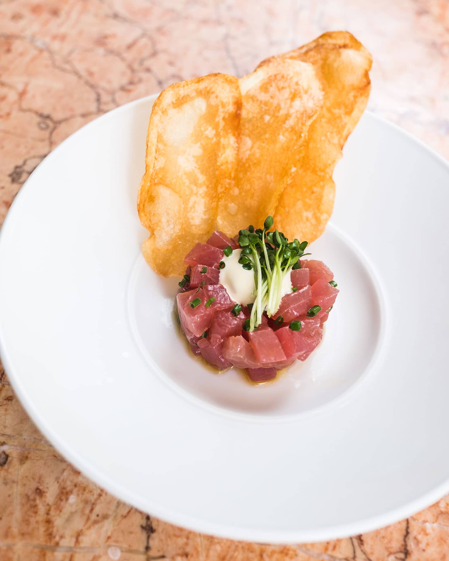 Tableview from above of Tuna Tartare served with potato crisp.